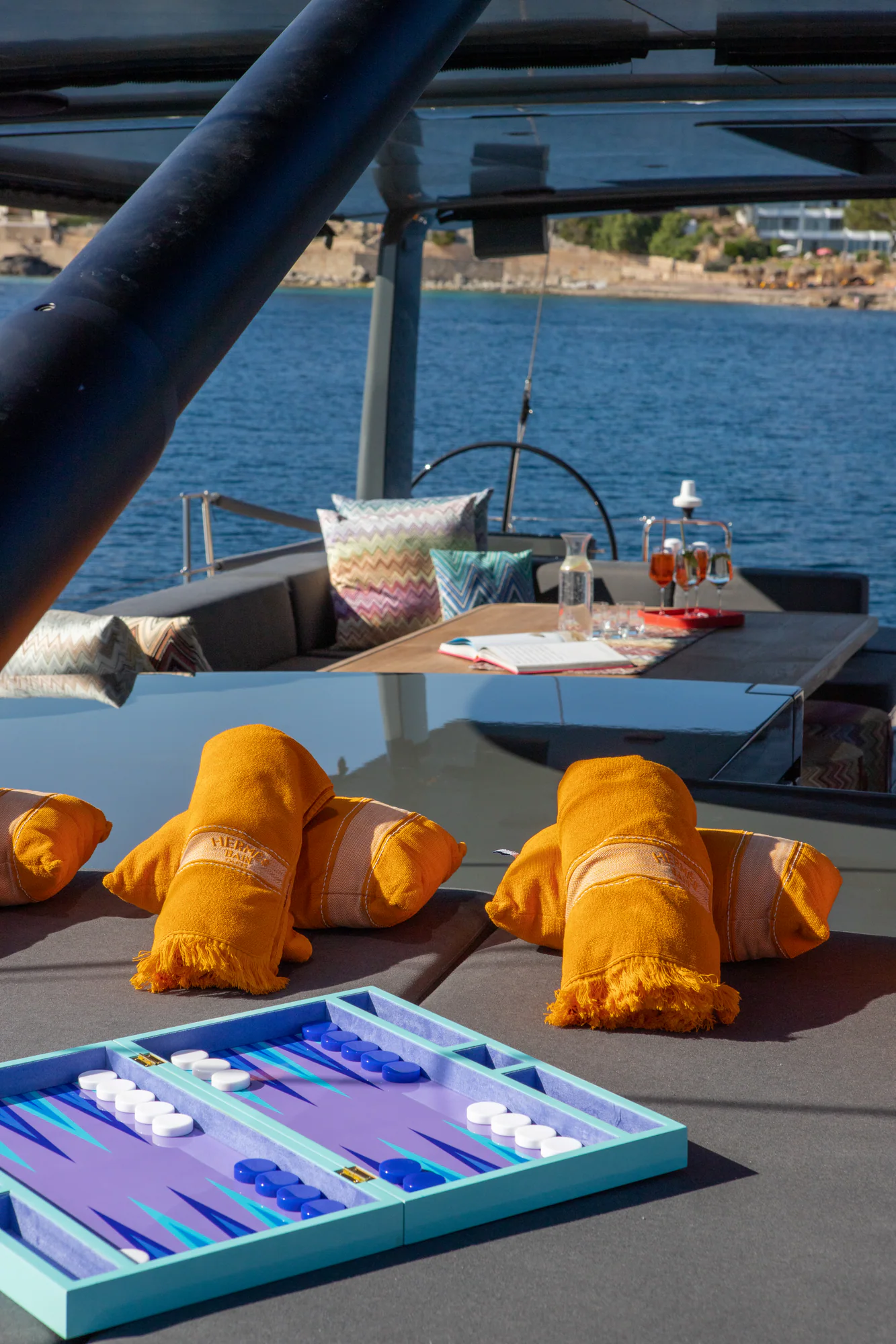 A backgammon board set up on the sunpads aboard Sailing Yacht W, the Mediterranean coast beyond