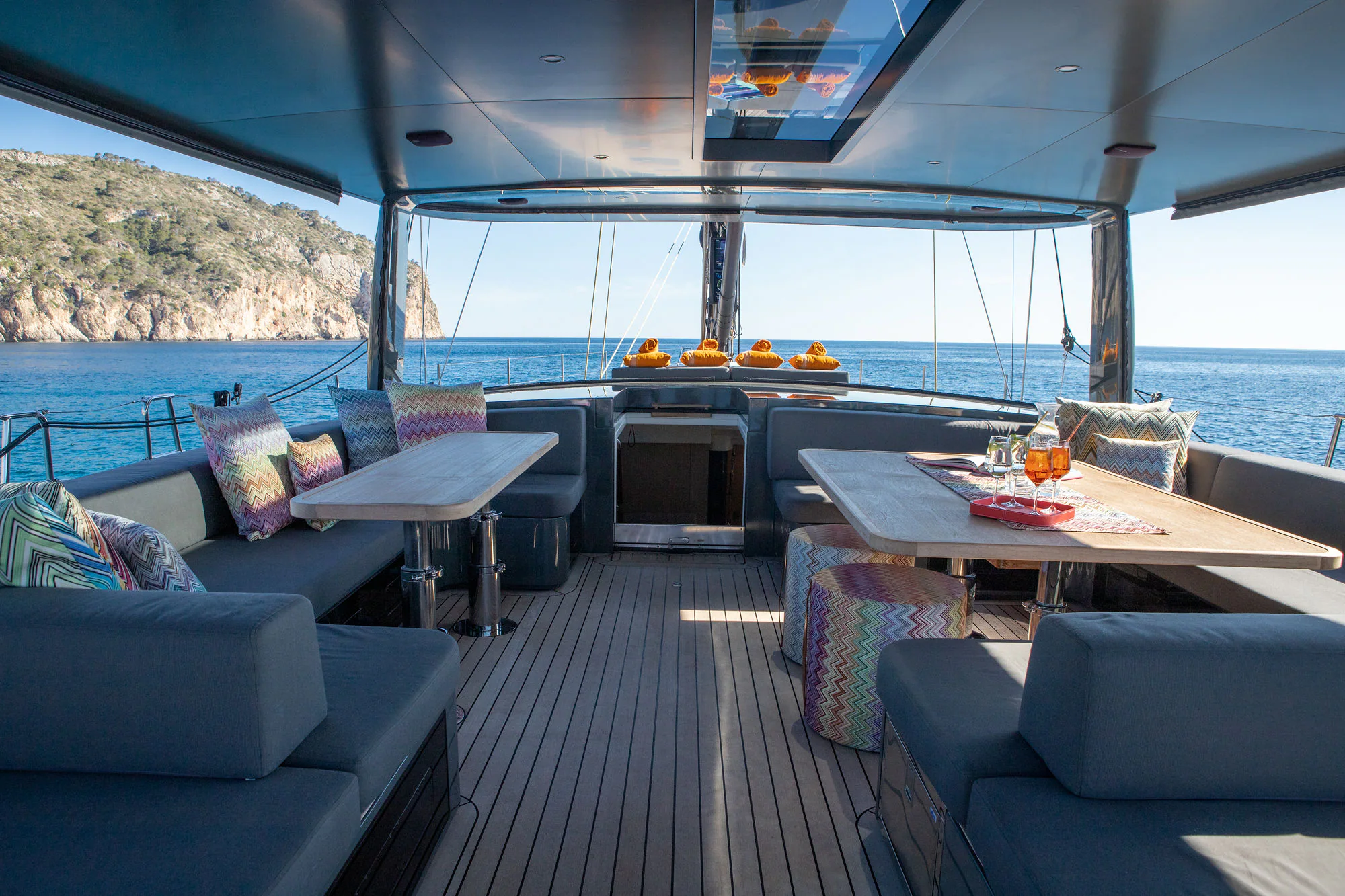 At the helm of Sailing Yacht W, carbon wheel and compass on the teak deck, Mediterranean coast beyond