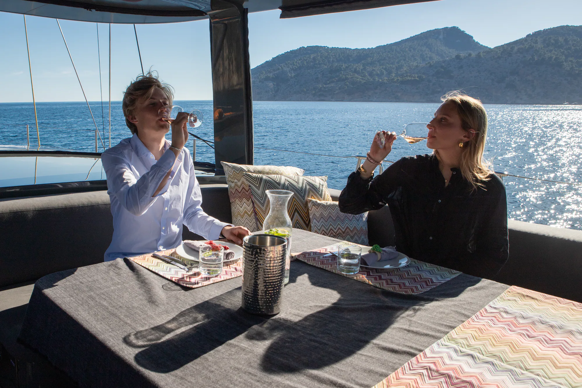 Two guests enjoying wine at the cockpit table aboard Sailing Yacht W
